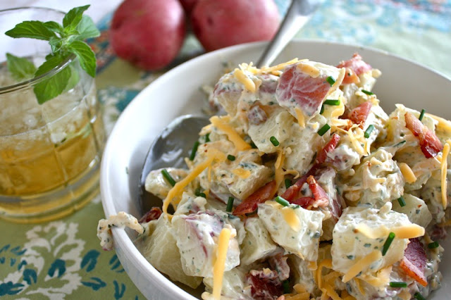 Loaded Baked Potato Salad - Potato Salad in a bowl with cheese, bacon, chives, and a cocktail, on green napkin