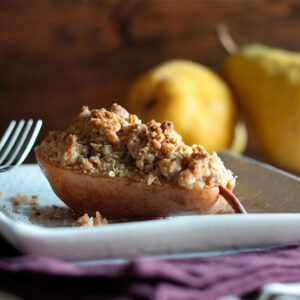 A half pear filled with crumble topping on a plate