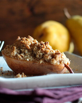 A half pear filled with crumble topping on a plate