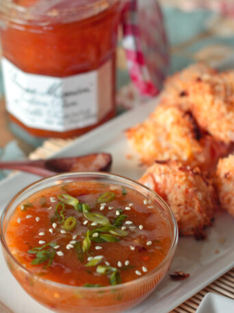 A bowl of sweet and spicy mirabelle golden plum dip with coconut shrimp