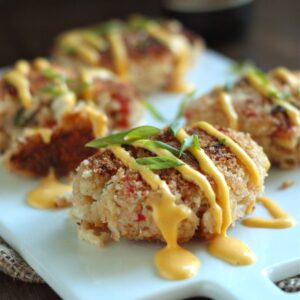 Close-up of IPA Crab Cakes drizzled with IPA hollandaise on a cutting board
