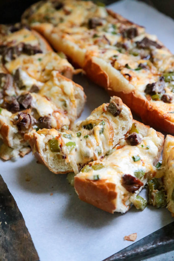 Cheesy Philly Cheesesteak Bread - sliced on a parchment paper background