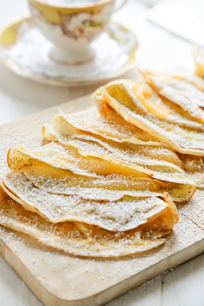 Lemon Poppyseed Crepes with Lemon Curd - on a cutting board with yellow and white tea cup
