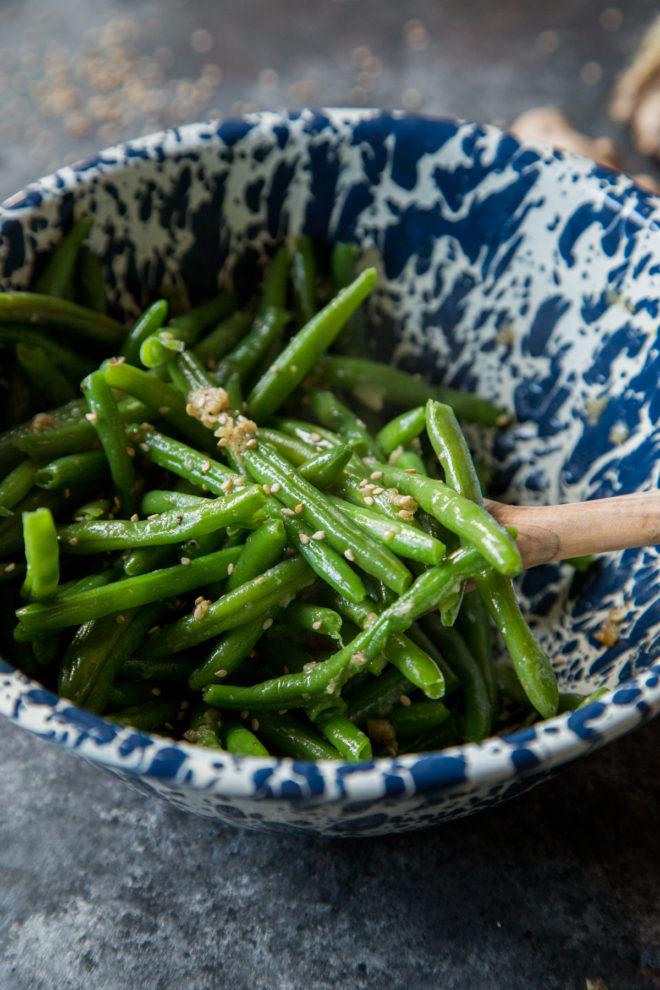 Green beans with sesame sprinkled on top in a blue and white bowl