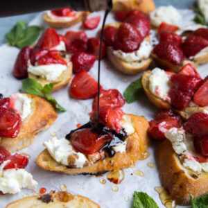 Honey Roasted Strawberry Bruschetta with Lavender Goat Cheese Strawberries on platter with balsamic vinegar drizzle