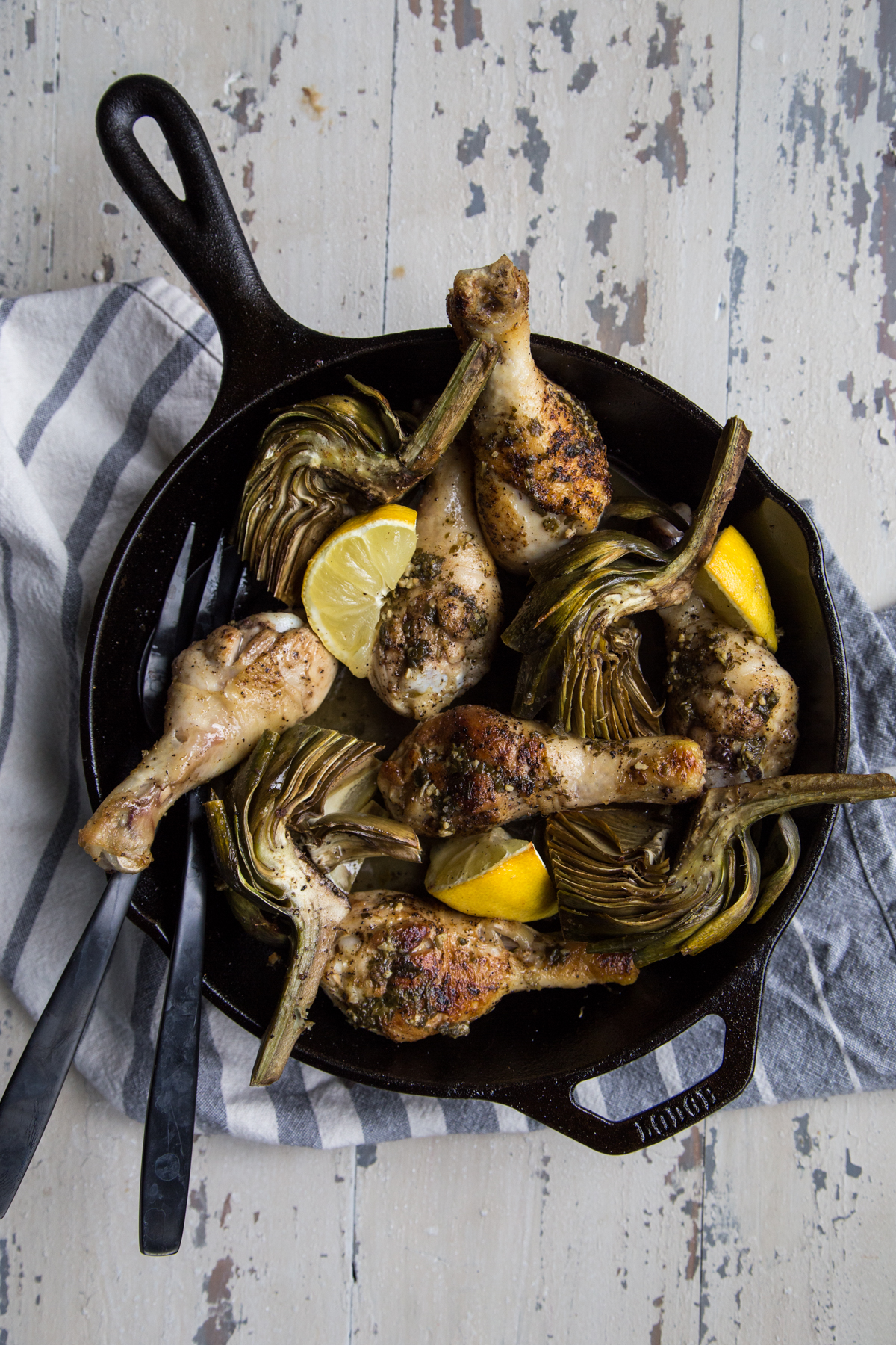 Roasted chicken drumsticks and artichokes in a skillet
