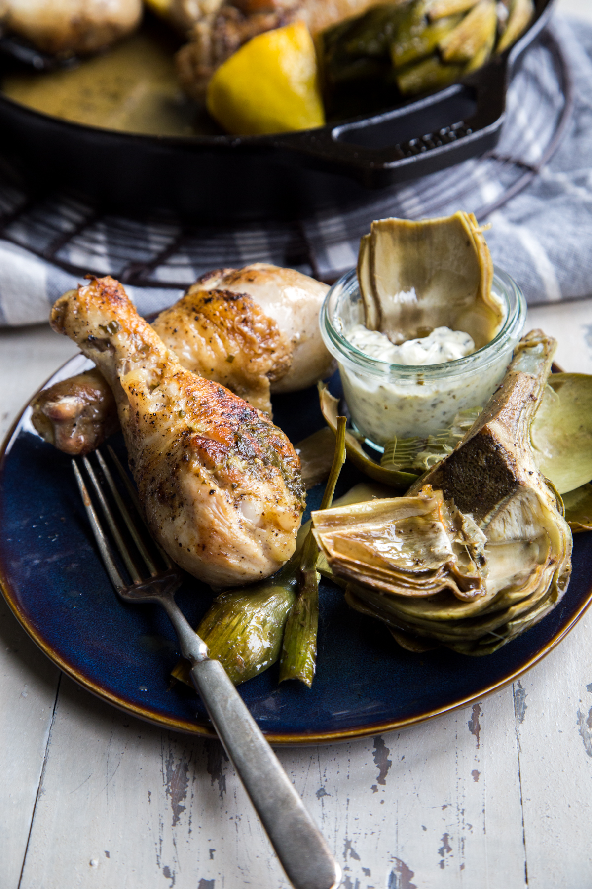 Roasted chicken drumsticks and artichokes on plate
