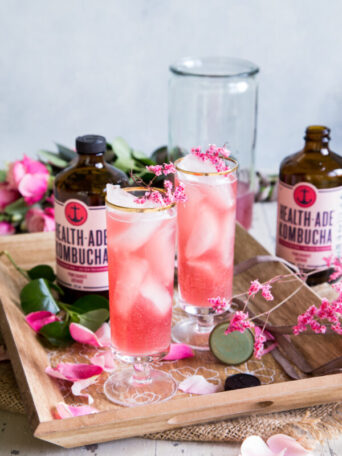 Pomegranate Kombucha St Germain Spritzer Cocktail with roses and two bottles