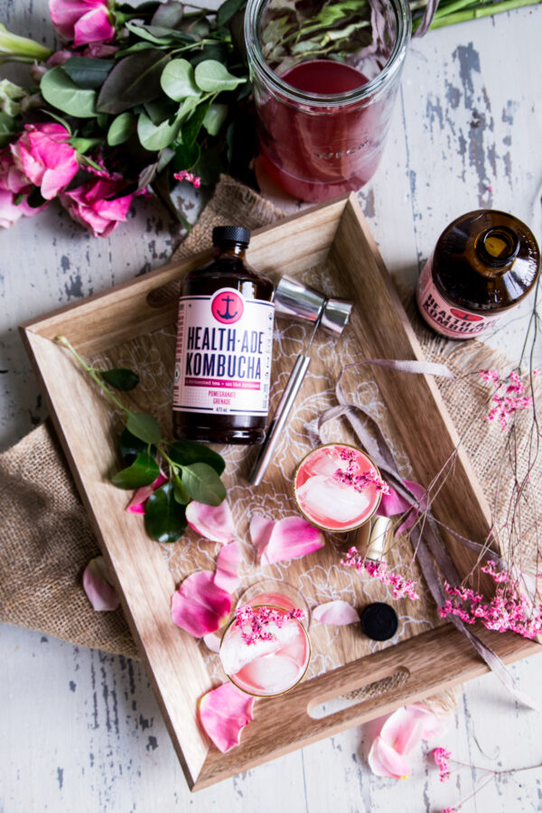 Pomegranate Kombucha St Germain Spritzer Cocktail overhead shot with rose petals, a wood serving tray