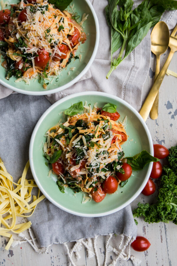 Rustic Tomato Kale Alfredo Pasta overhead with green plates and fresh pasta around it