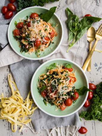 Rustic Tomato Kale Alfredo Pasta overhead with kale and tomato on white background