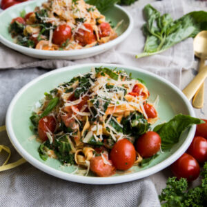 Rustic Tomato Kale Alfredo Pasta up close on green plates with rustic napkins