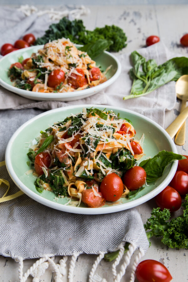 Rustic Tomato Kale Alfredo Pasta up close on green plates with rustic napkins