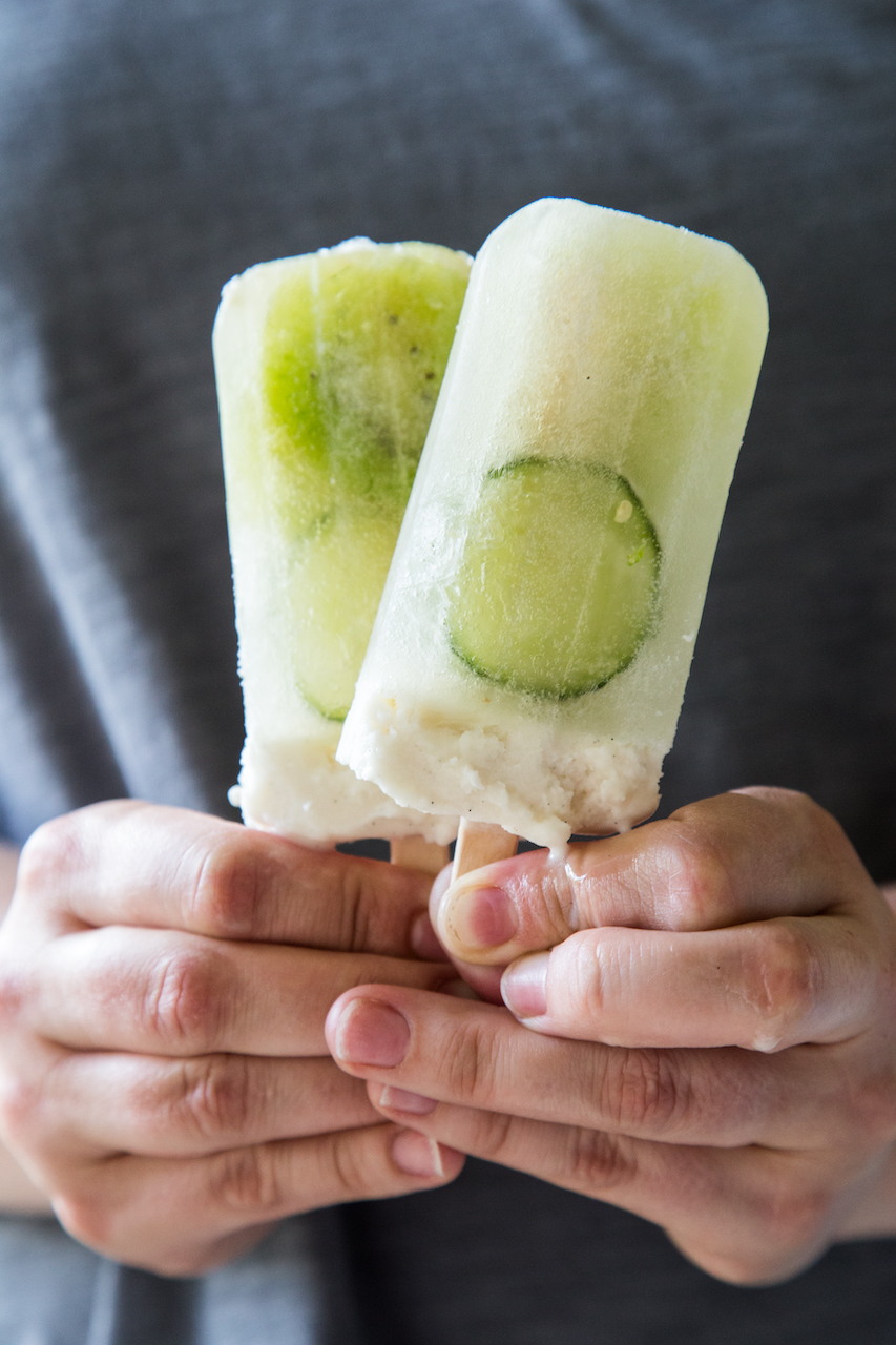 Kiwi Jalapeno Cucumber Popsicles with Coconut Cream being held in hand