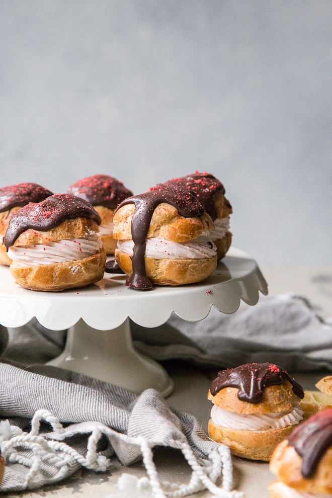 strawberry cream puffs on a cake stand with a marbled background