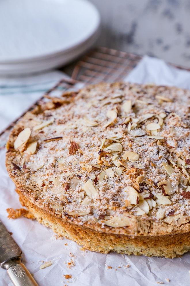 easy Italian almond tea cake unsliced with toasted almonds on a copper wire cooling rack