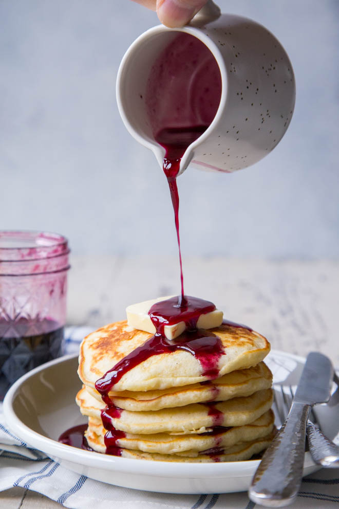 homemade blueberry pancake syrup on a stack of pancakes