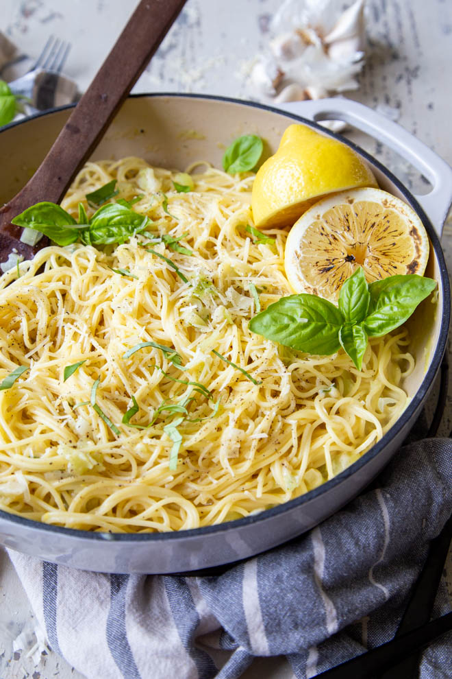 One Pot Lemon Basil Pasta in a white cast iron pan with parmesan and basil sprinkled on top