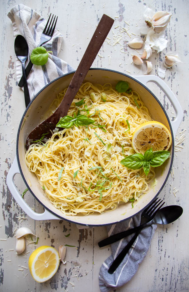 One Pot Lemon Basil Pasta with a wooden spoon nestled in and a charred lemon and basil leaves on top