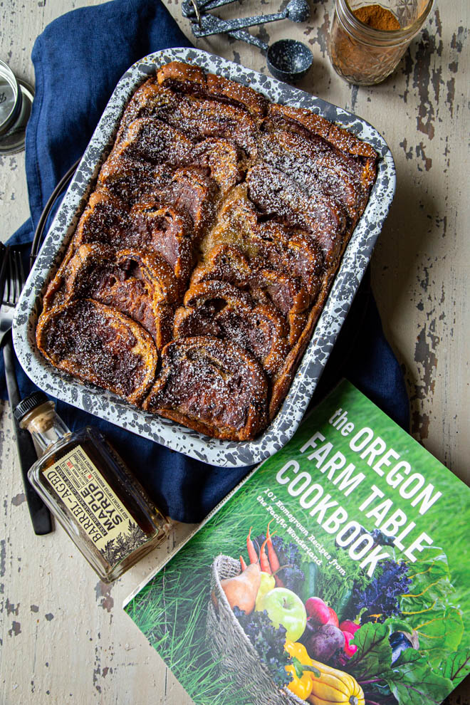 baked french toast in a gray and white speckled dish with closed cookbook, shot overhead
