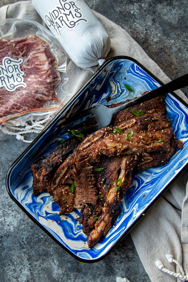 Asian Grilled Flanken Short Ribs shot overheat in blue and white dish with Widnor Farms frozen beef alongside