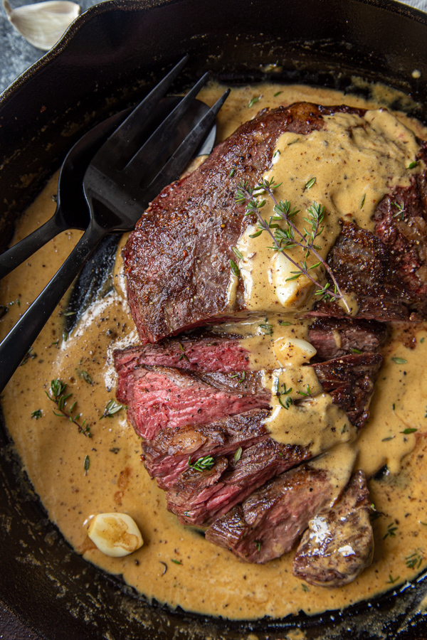 Cast Iron Bavette Steak with Whiskey Garlic Cream Sauce overhead in a pan with sauce and thyme on top