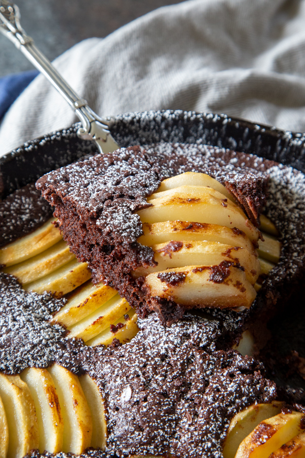 Chocolate chai and pear skillet cake in a cast iron skillet with a slice removed