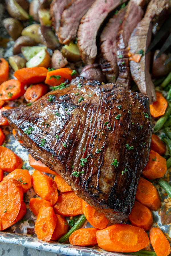 sheet pan steak and veggies dinner with flank steak on a bed of roasted vegetables