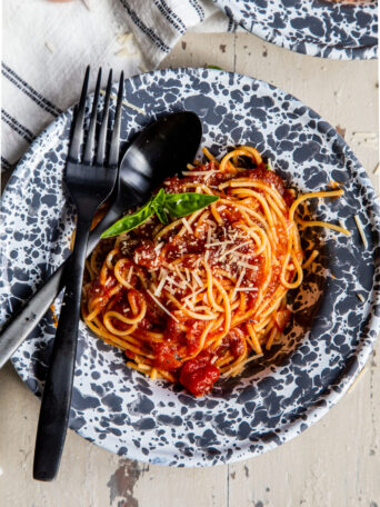 Overhead shot of bowl with spaghetti and pasta sauce with fork and spoon