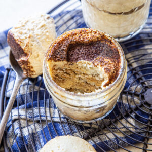 Two jars of pumpkin spice tiramisu with spoonful of cream scooped out and two shortbread cookies