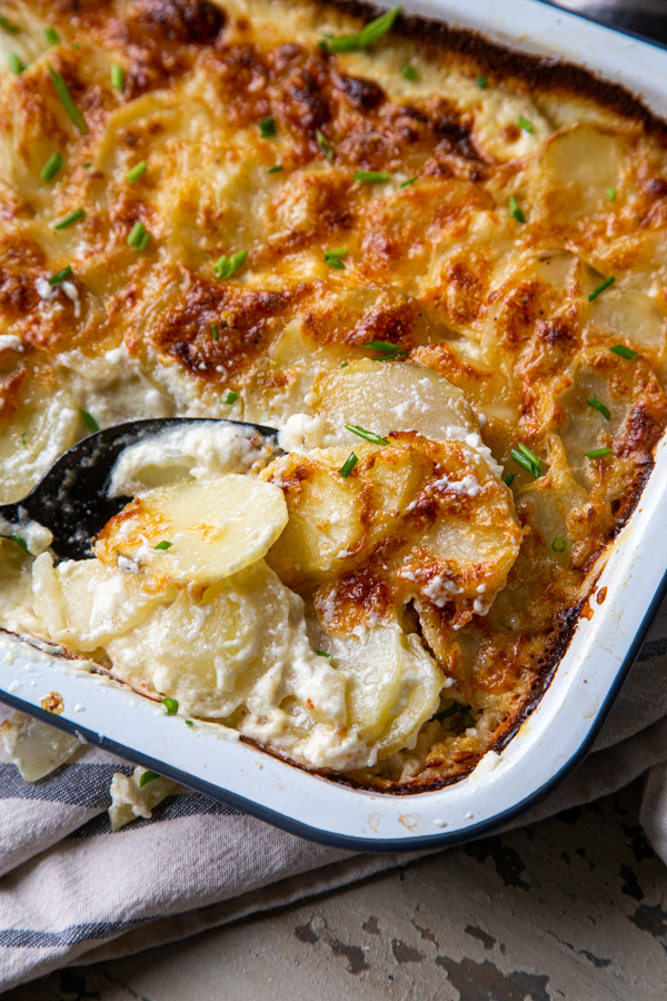 Closeup of cheesy potatoes au gratin in baking dish with spoon
