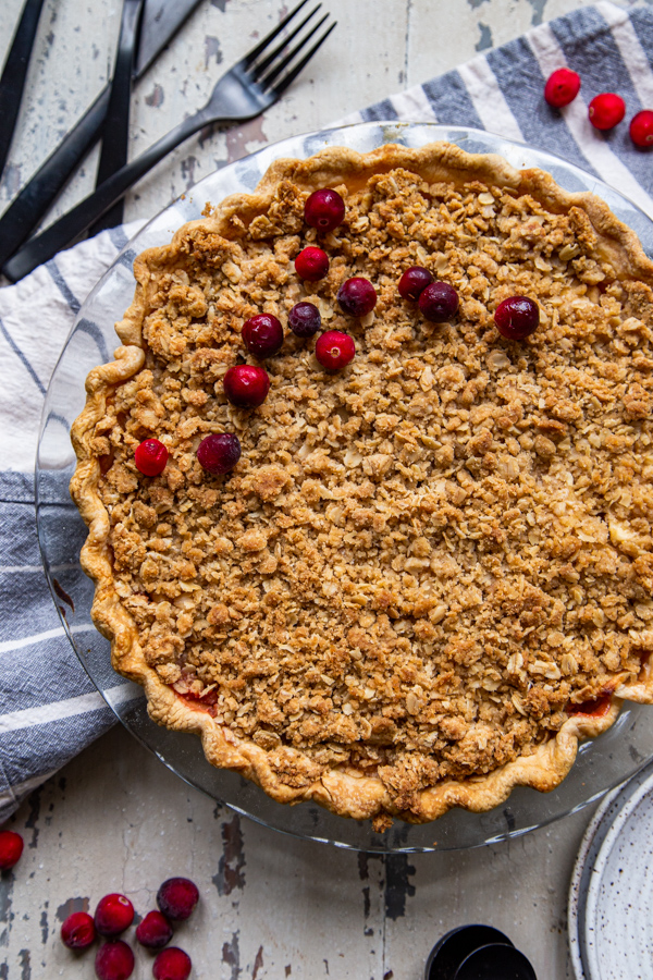 Whole Cranberry Dutch Apple Pie in glass dish with cranberries scattered on top