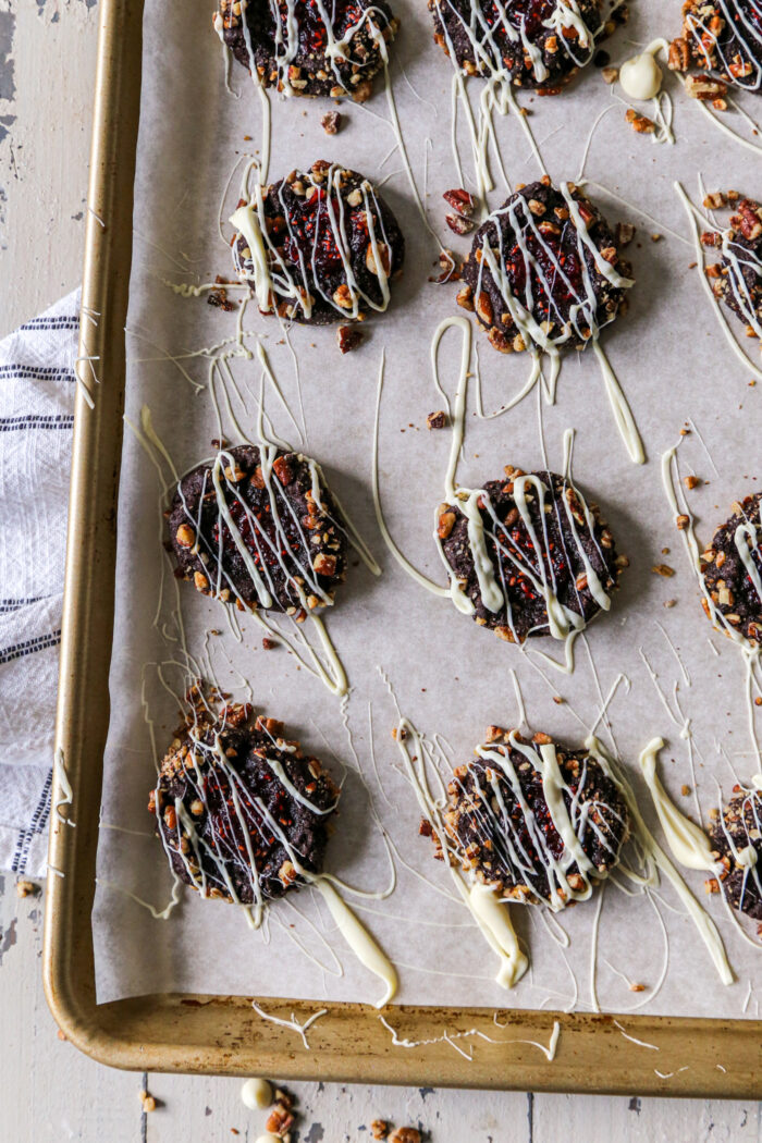 Chocolate raspberry thumbprint cookies on a parchment lined baking sheet, shot from overhead