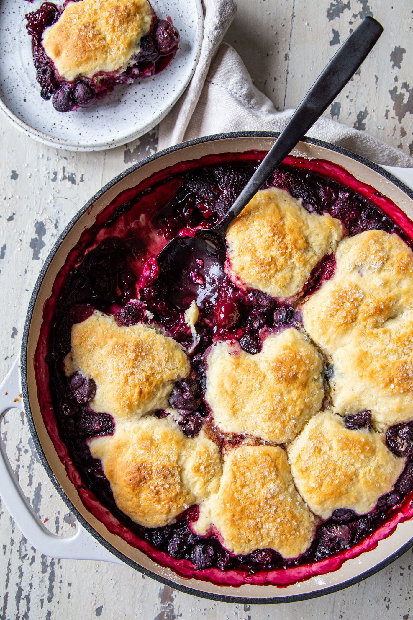 Easy cast iron berry cobbler in white cast iron pan shot over head on white distressed board