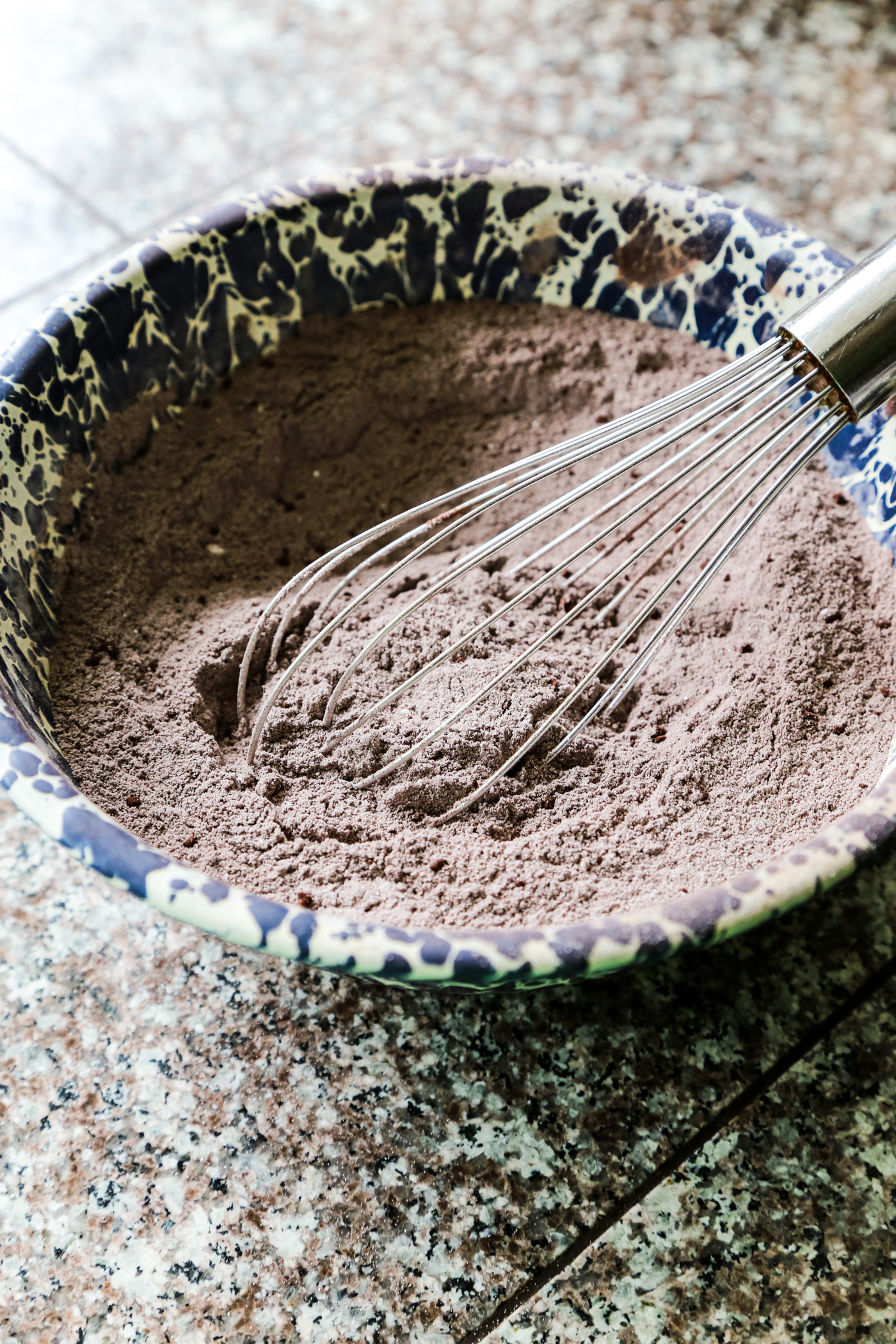 Chocolate pudding ingredients mixed together in a bowl with a metal whisk. 
