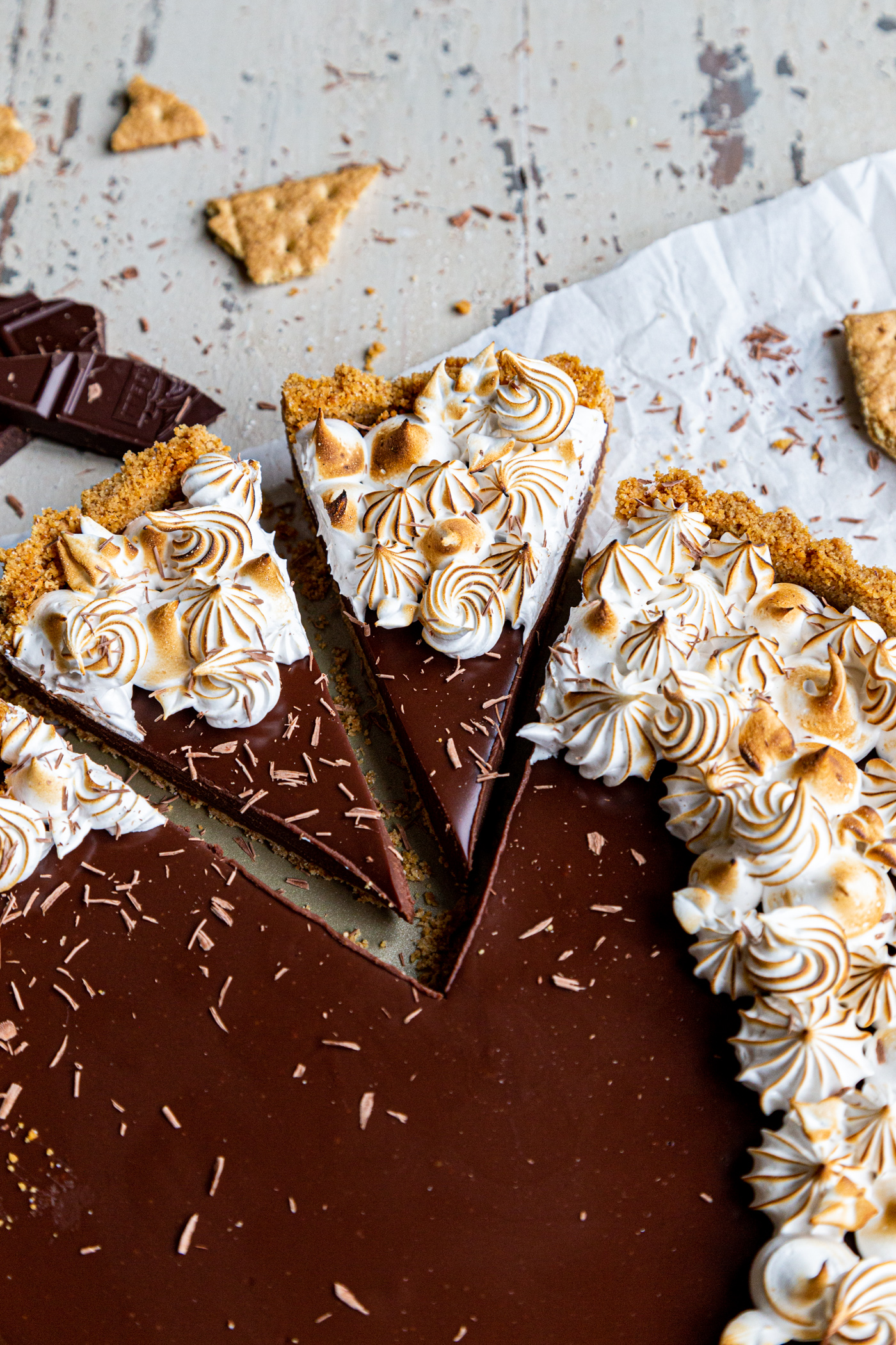 Chocolate s'mores tart with two slices cut out of it with chocolate shavings on top