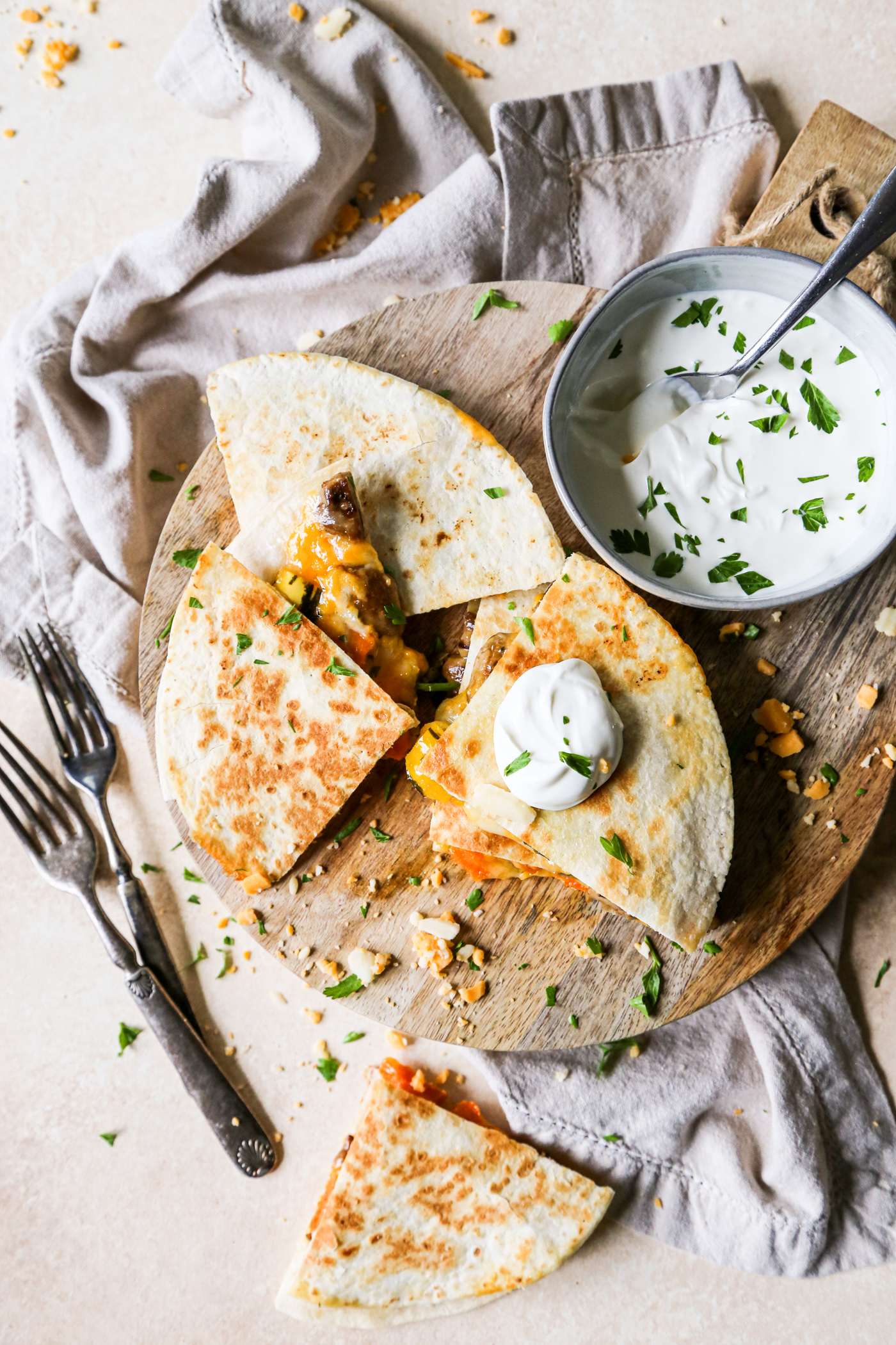 Steak Mushroom and Squash Quesadilla is a luxury leftover dream recipe on a wood cutting board next to a bowl of sour cream