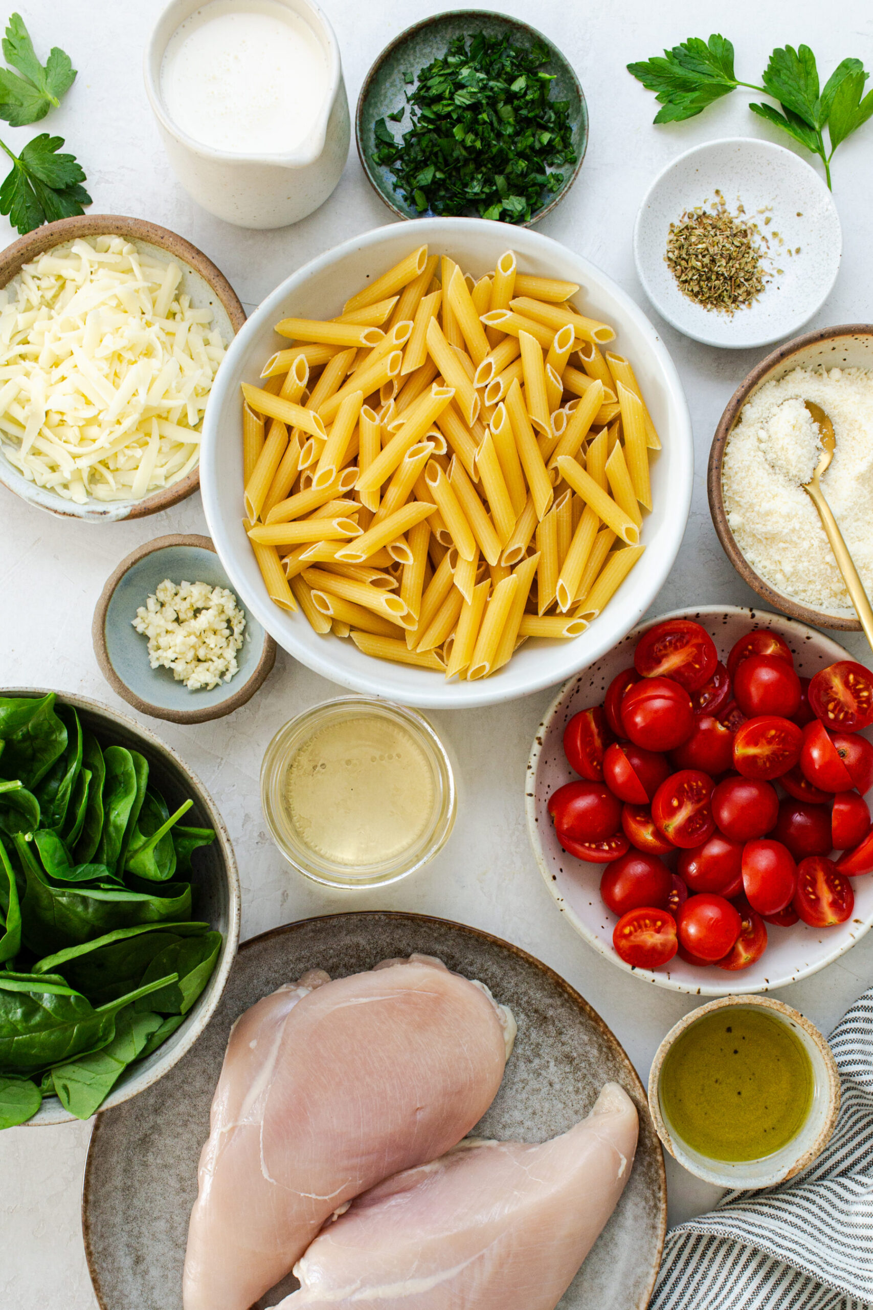 Overhead shot of all ingredients for one pot chicken Florentine pasta in white or handmade porcelain bowls